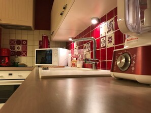 Una cocina con microondas, cafetera y un electrodoméstico rojo en la encimera.