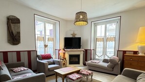 A living room with a fireplace, two sofas, a coffee table, and a television. - Centre Cauterets, appartement 72m2 pr 7 personnes (Cauterets)