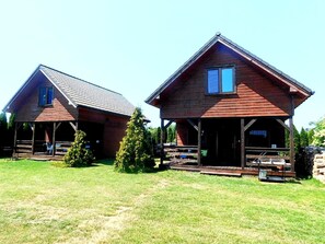 Cabins feature porches and sit on a grassy lawn surrounded by trees.