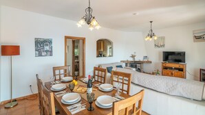A dining area with a wooden table set for four, a chandelier, and a television in the background. - Beautiful Villa Botin, 9 Pers, Heated pool, Wifi, BBQ,Petfriendly, magnific view (Comares)