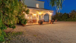 A house with a gravel driveway, a covered patio with outdoor furniture, and potted plants. - Beautiful Villa Botin, 9 Pers, Heated pool, Wifi, BBQ,Petfriendly, magnific view (Comares)