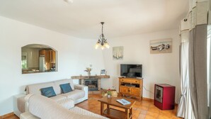 A living room with a sofa, coffee table, fireplace, television, and a small red speaker. - Beautiful Villa Botin, 9 Pers, Heated pool, Wifi, BBQ,Petfriendly, magnific view (Comares)