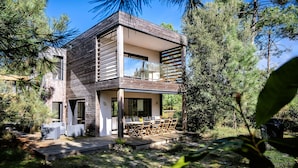 Una casa moderna de dos pisos con un balcón, rodeada de  árboles.