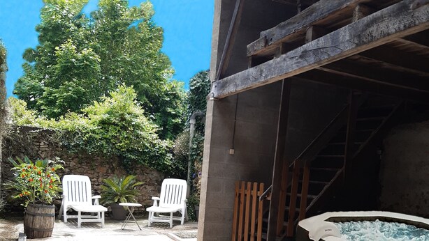 Een terras buiten met twee witte stoelen, een kleine tafel, een hottub en enkele vogels op de grond.