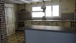 Een keuken met een groot eiland, een fornuis, oven en een hangende lamp.