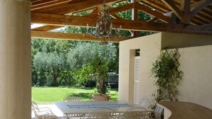 An outdoor patio with a table and chairs, a chandelier, and a view of a garden. - LA BASTIDE D'ANDRÉA, PRESTIGIOUS VILLA FOR 12 PEOPLE, NOT OVERLOOKED (Martignargues)