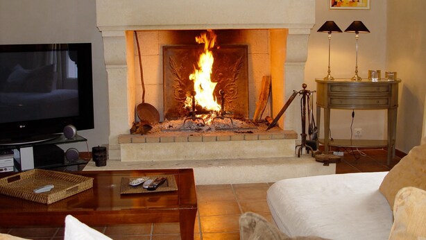 A living room with a fireplace, a television, and a table with remote controls. - LA BASTIDE D'ANDRÉA, PRESTIGIOUS VILLA FOR 12 PEOPLE, NOT OVERLOOKED (Martignargues)