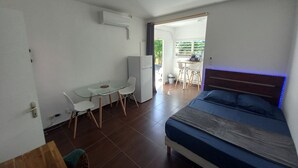 A bedroom with a bed, a desk, and a chair. There is a kitchenette in the background. - Studio Oncle Sam: pool and beach access. Ideal for vacations or weekends for two (Le Gosier)