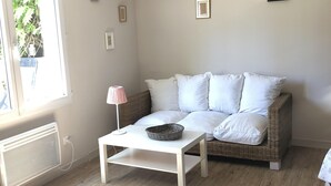 A room with a white sofa, a white coffee table, and a wicker basket. There are three framed pictures on the wall.