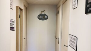A hallway with wooden flooring, a 'Welcome' sign, and various signs on the walls.