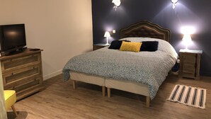 A bedroom with a bed, a television on a dresser, and two bedside lamps.
