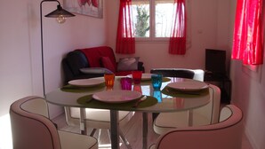 Un coin repas avec une table en verre, quatre chaises et un canapé en arrière-plan.