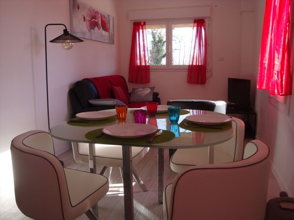 Un comedor con una mesa de vidrio, cuatro sillas y un sofá al fondo.