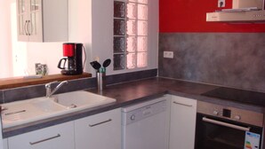 Une cuisine moderne équipée d’un lave-vaisselle, d’un four et d’une machine à café posée sur le plan de travail.
