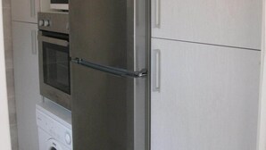 Una cucina compatta con frigorifero in acciaio inossidabile, forno integrato e lavatrice.