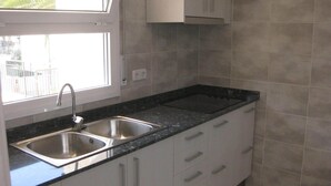 Una cucina con un lavello doppio, mobili bianchi e una finestra.