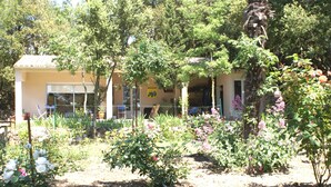 A building with a yellow sign, surrounded by a garden with various plants and flowers. - Quiet cottage near Carcassonne pool (Ventenac-Cabardès)