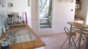 A compact kitchen with a sink, a coffee maker, and a microwave. There is a window with a view of a stone wall and greenery outside. - Quiet cottage near Carcassonne pool (Ventenac-Cabardès)