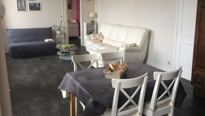 A living room with a dark blue sofa, a white sofa, a dining table with chairs, and a small table with a basket of bread. - Apartment hyper center of Saint Omer (Saint-Omer)