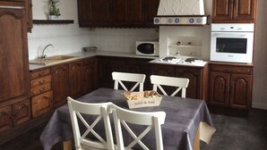A kitchen with wooden cabinets, a microwave, an oven, a sink, and a table with chairs. - Apartment hyper center of Saint Omer (Saint-Omer)