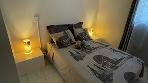 Een slaapkamer met een bed, nachtkastjes en een lamp.