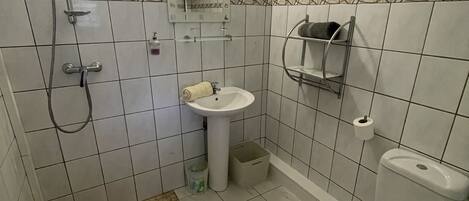A bathroom with a shower, sink, toilet, and a small window.