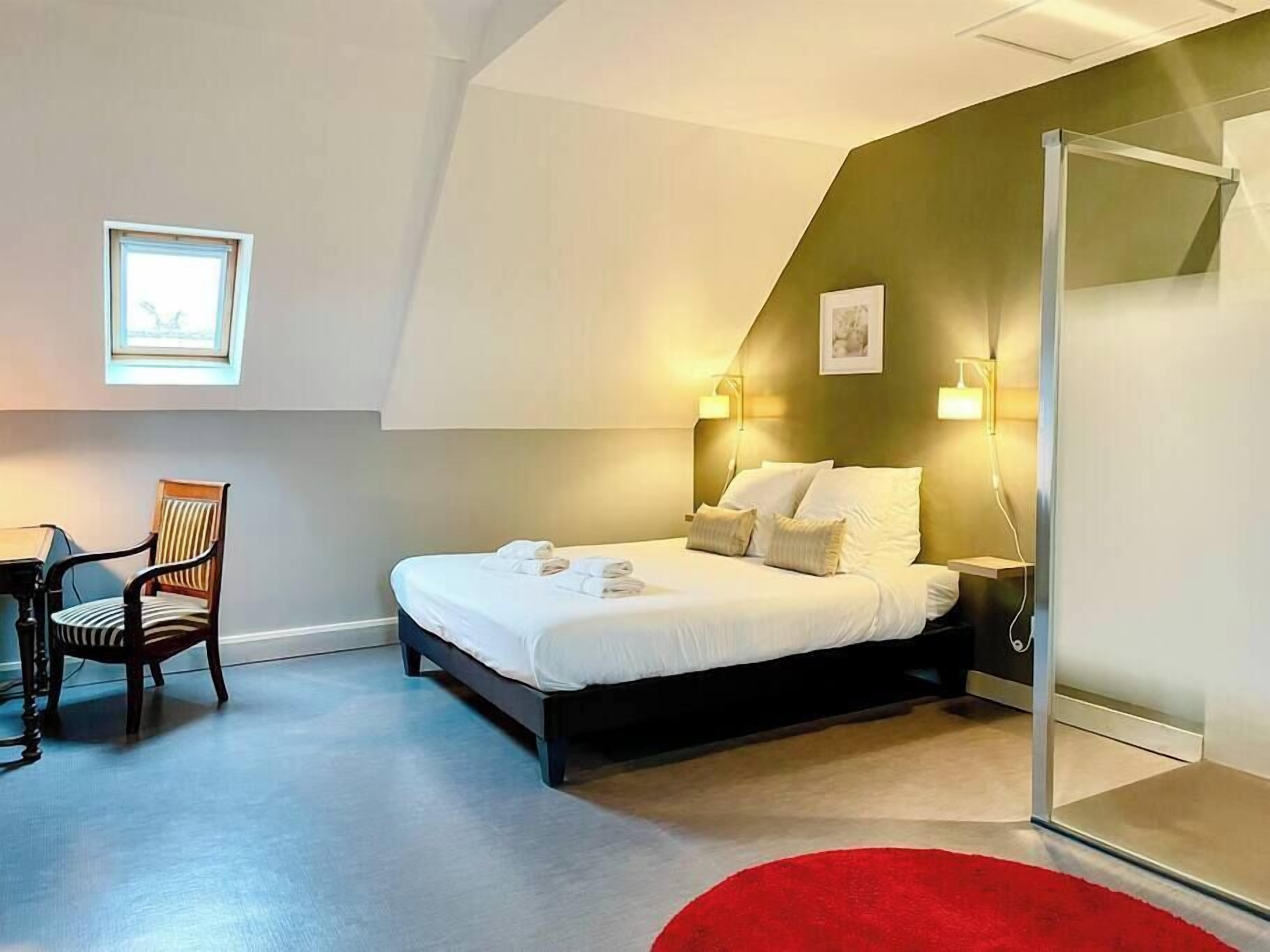 Een moderne hotelkamer met een bed, een bureau en een stoel.