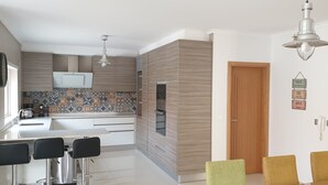 Una cocina moderna con salpicadero de azulejos, armarios de madera y un área de comedor con sillas.