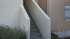 A concrete staircase leading to a door, surrounded by a beige wall and some greenery. - Spacious and pleasant T3 with pool near beach, port, leisure island  (Agde)