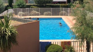 A residential building with a swimming pool, surrounded by a white fence and various plants. - Spacious and pleasant T3 with pool near beach, port, leisure island  (Agde)