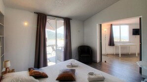A bedroom with a bed, a chair, a desk, and a view through a glass door. - Beautiful holiday home, charm and rest. Seaview! (Viggianello)