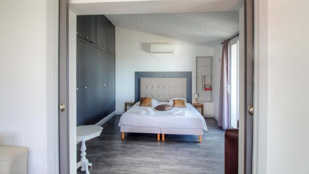A bedroom with a bed, bedside tables, a wardrobe, and an air conditioning unit. - Beautiful holiday home, charm and rest. Seaview! (Viggianello)
