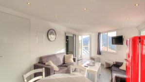 A modern living room with a sofa, a dining table, and a TV. - Beautiful holiday home, charm and rest. Seaview! (Viggianello)