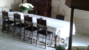 Une salle à manger avec une table blanche, des chaises en bois, un lustre et un grand buffet en bois.