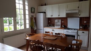 Una cocina con armarios blancos, una estufa, un fregadero y una ventana con persianas.