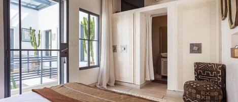Een slaapkamer met een groot bed, een raam met uitzicht op een balkon en een stoel.