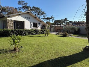 A house with a stone facade, a well-maintained lawn, and a pergola structure. - Villa Dune & Ocean 100 m from the beach (Labenne)