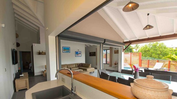 A modern kitchen with a large island, a sink, and a dining area with outdoor seating.