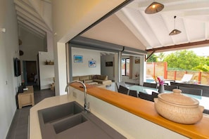 Een moderne keuken met een groot eiland, een spoelbak en een eetgedeelte met buitenplaatsing.