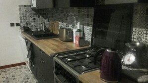 Cozinha equipada com fogão a gás, chaleira e máquina de café.