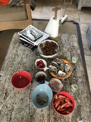 A dining table with various food items including seafood, a bowl of shrimp, and a plate of oysters.