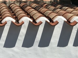 A row of terracotta roof tiles with white edges, likely part of a building's exterior.