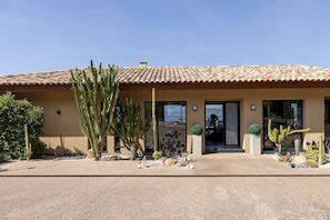 A building with a tiled roof, a door, and a small garden with cacti.