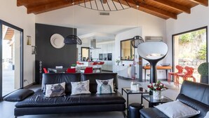 Un salon moderne avec un canapé noir, une table basse et un coin repas avec des chaises rouges.