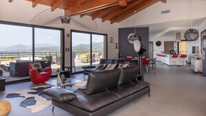 A spacious living area with a leather sofa, red chair, and a large window overlooking mountains.