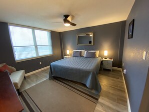 Relax in this serene bedroom with a large bed, bedside tables, and a ceiling fan.