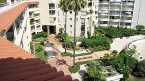 Un hôtel à plusieurs étages doté de balcons, d’une cour intérieure agrémentée de palmiers et d’un espace piscine.