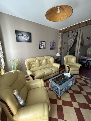 A living room with a checkered floor, a sofa, a chair, a coffee table, and a hanging light fixture.