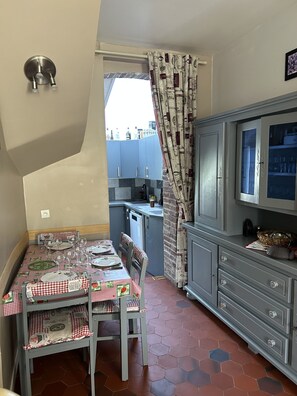 A compact kitchen with a dining table set for four, a small island, and a cabinet with glass doors.