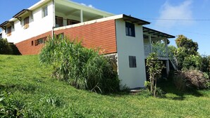 A two-story house with a red and white exterior, a covered porch, and a grassy yard. - GÎTE LES PIMENTIERS DE PAPAYE (Saint Claude)